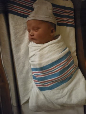 Newborn Dylan Fusting wrapped in a hospital blanket and wearing a knit cap