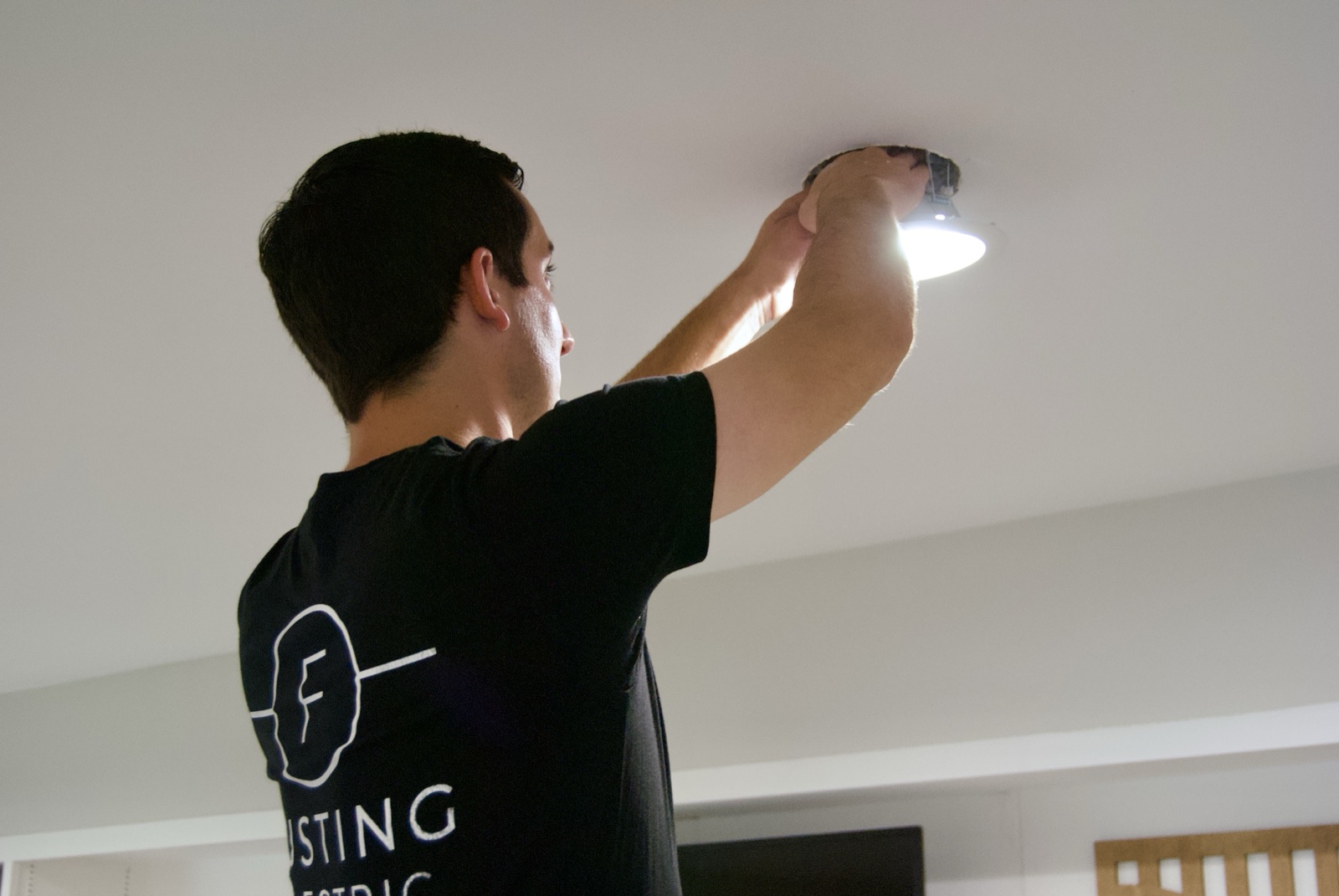 Stephen Fusting installing a recessed light while wearing a Fusting Electric shirt